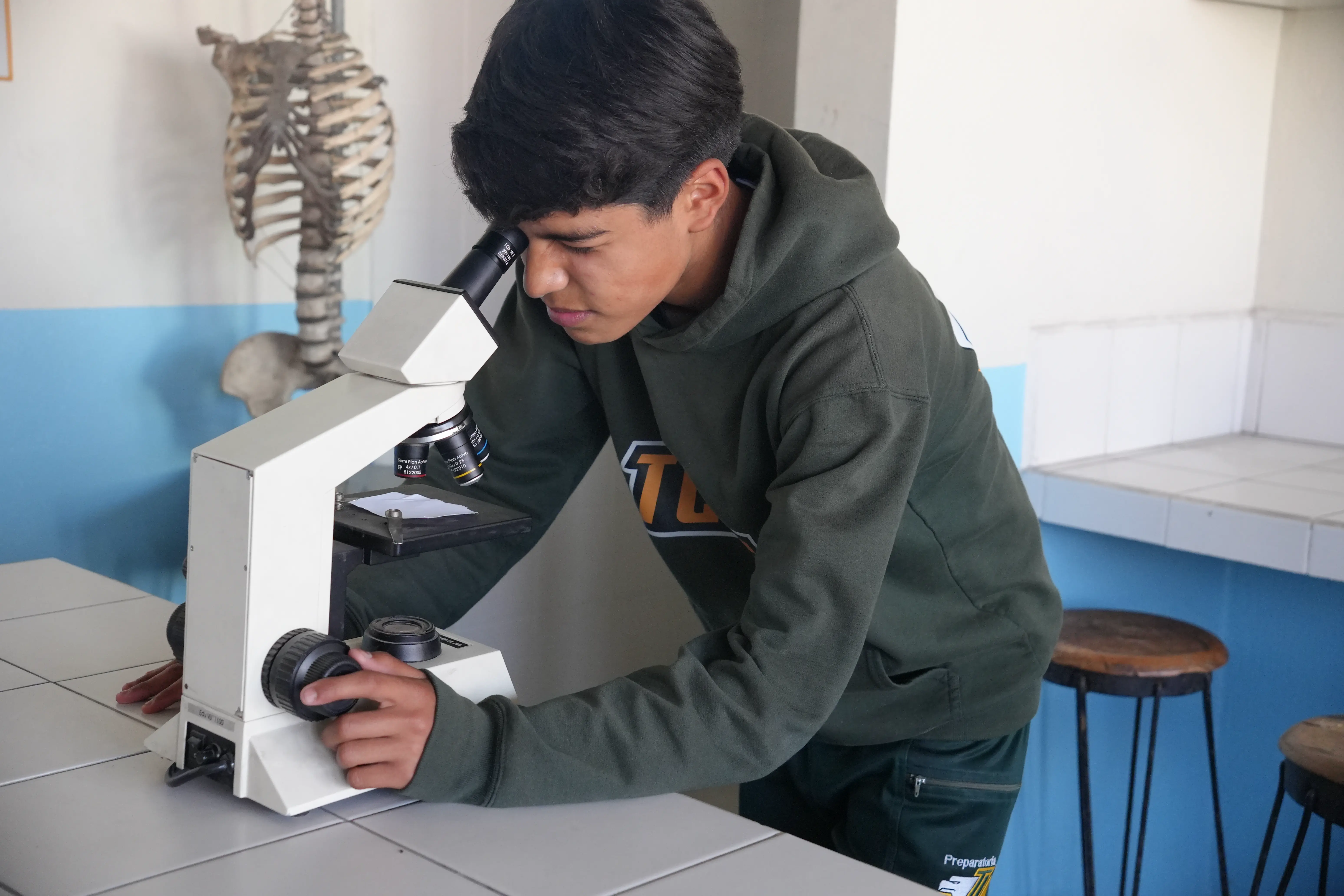 Alumno trabajando en laboratorio con microscopio